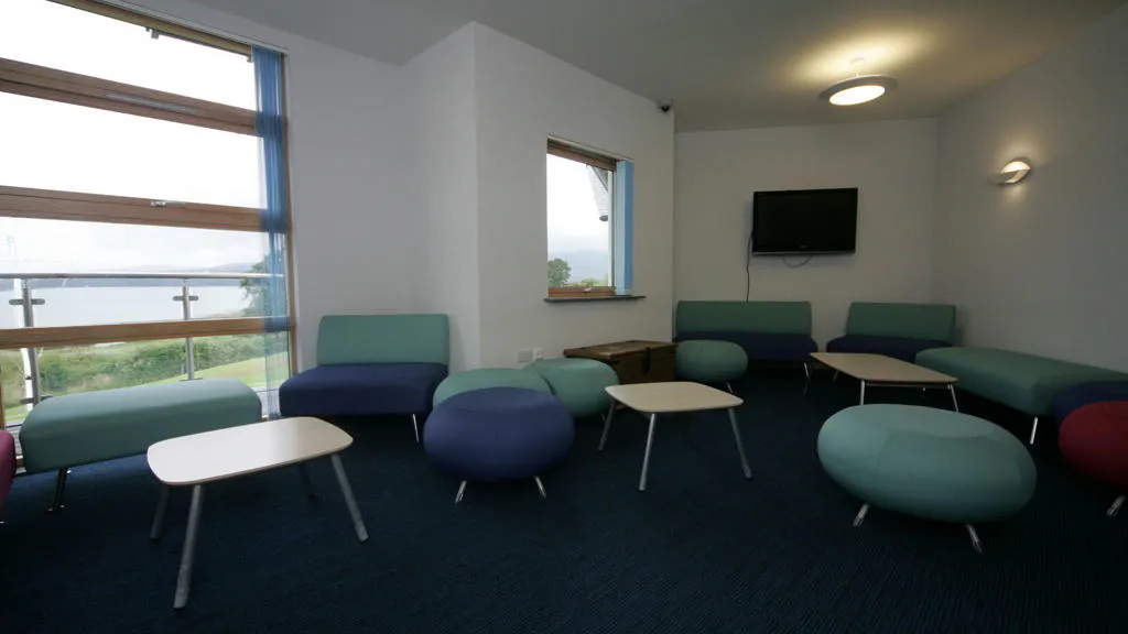 A room with mounted television, tables and chairs.