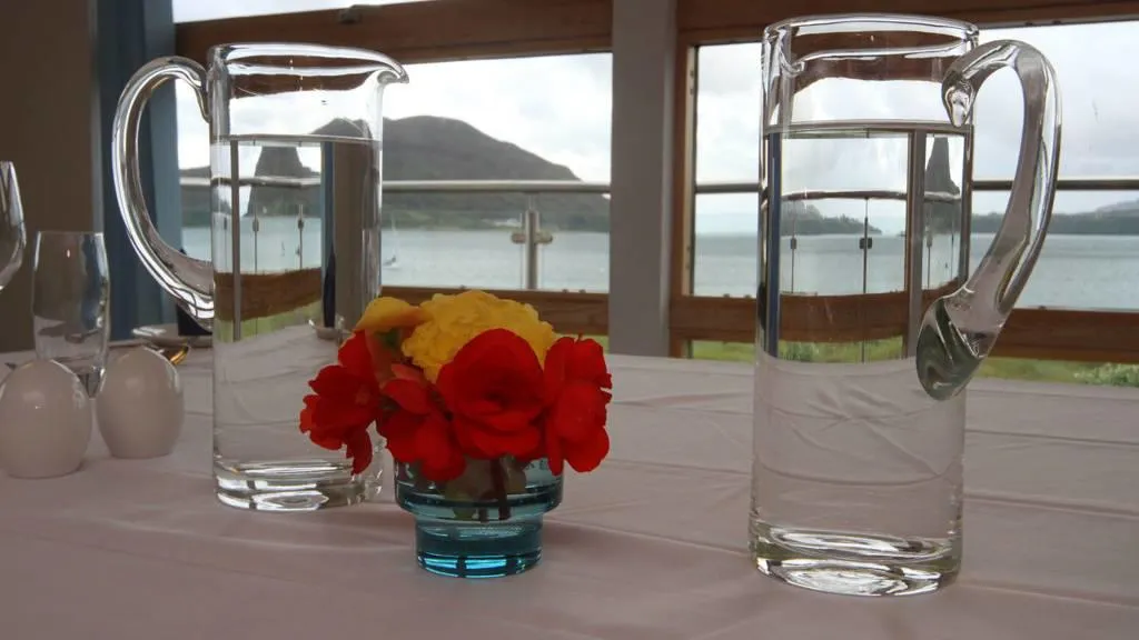 Flowers and water jugs on a white table.