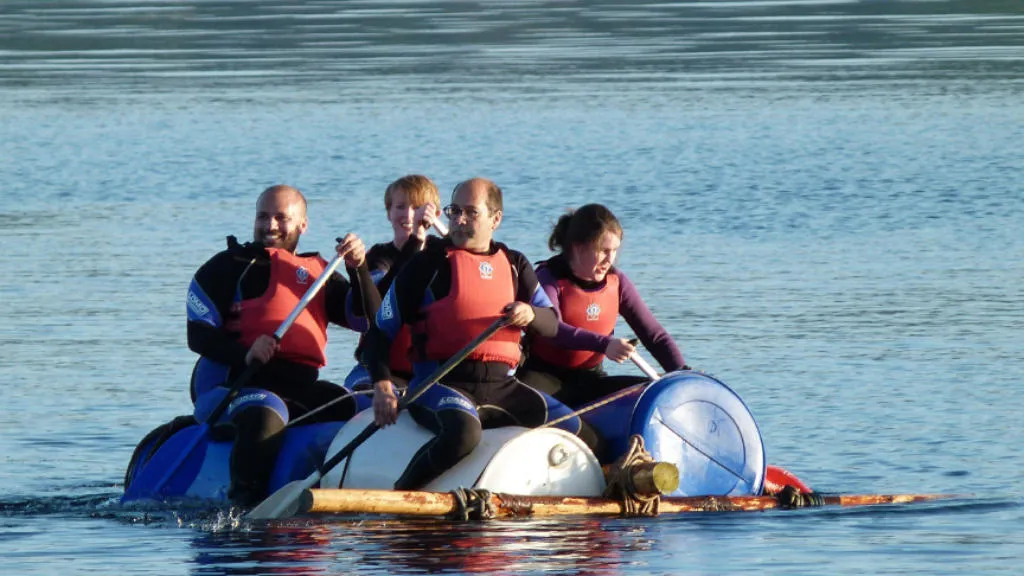 4 people rowing on board a makeshift raft.