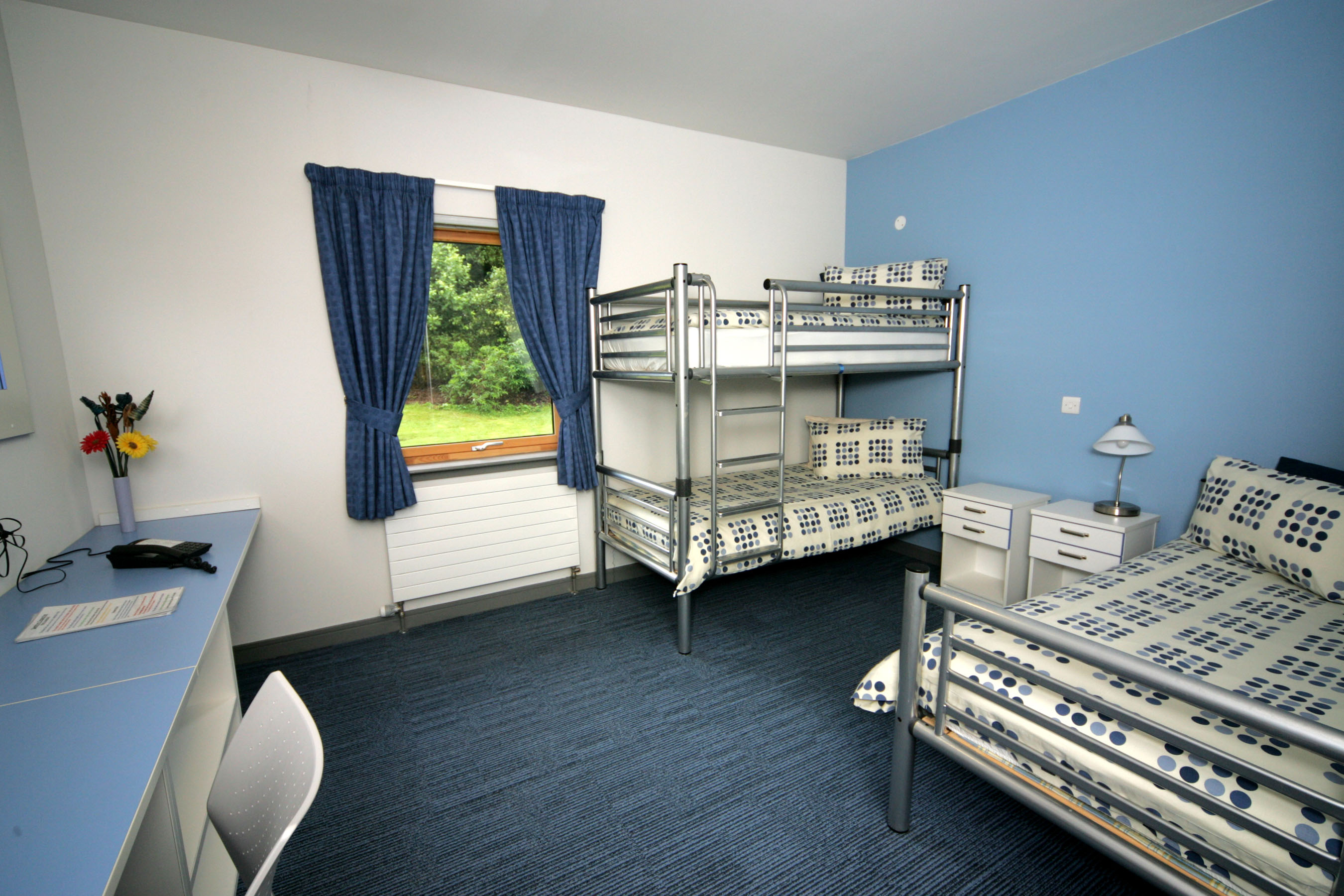Room with double bed bunk bed and desk.