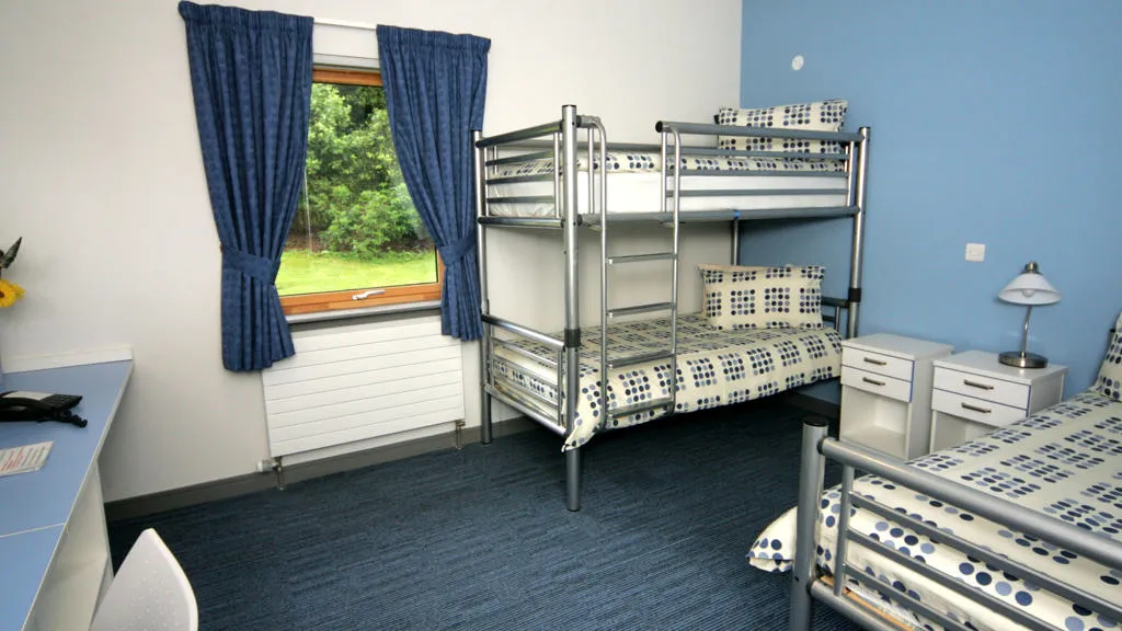Room with double bed bunk bed and desk.