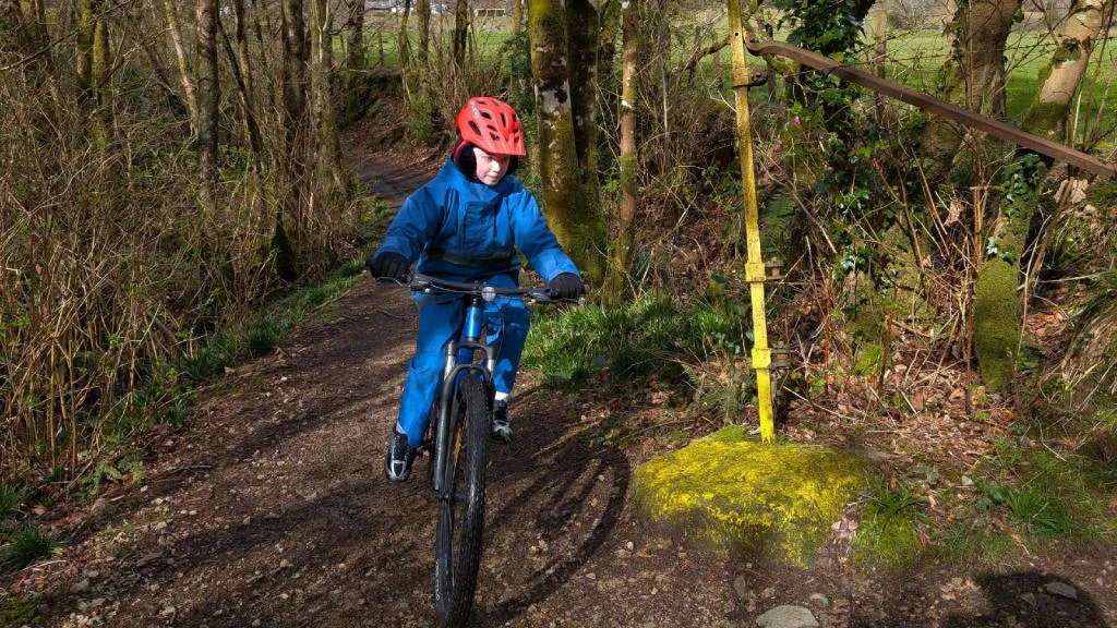 Child on a bike, cycling through a forest trail.
