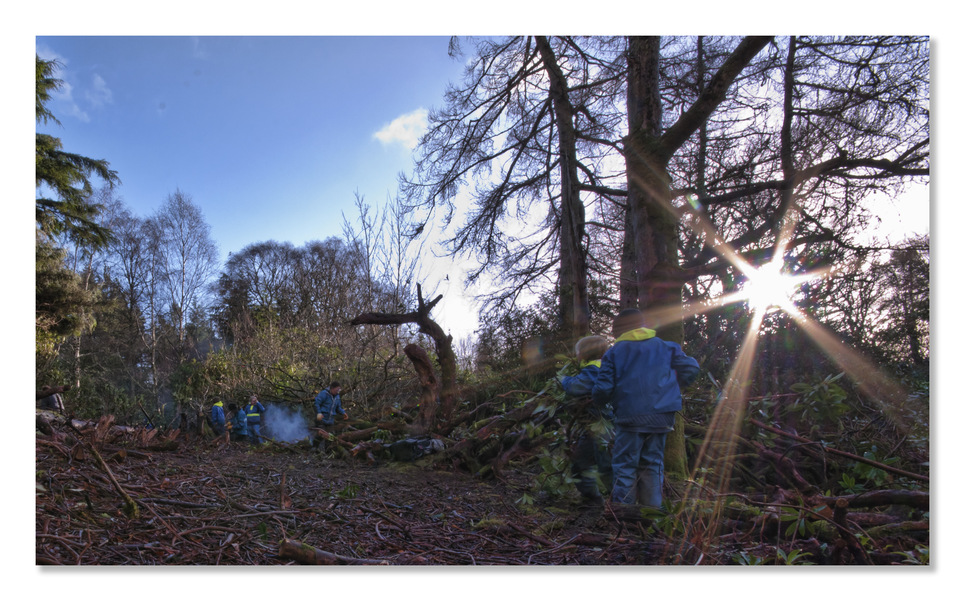 Children in a forest clearing with the sun setting.