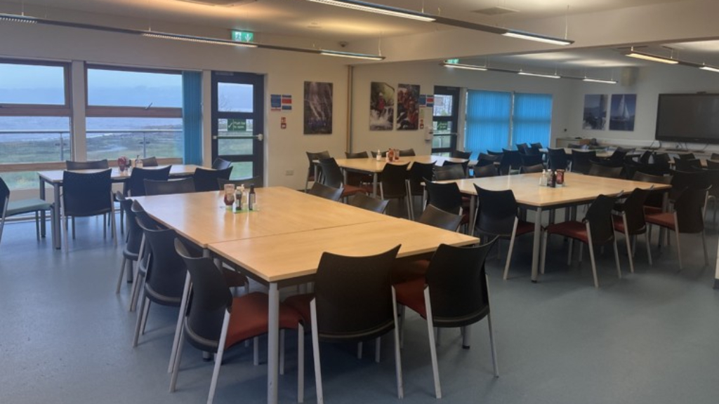 Six tables with chairs around them, with condiments in the middle of each table.