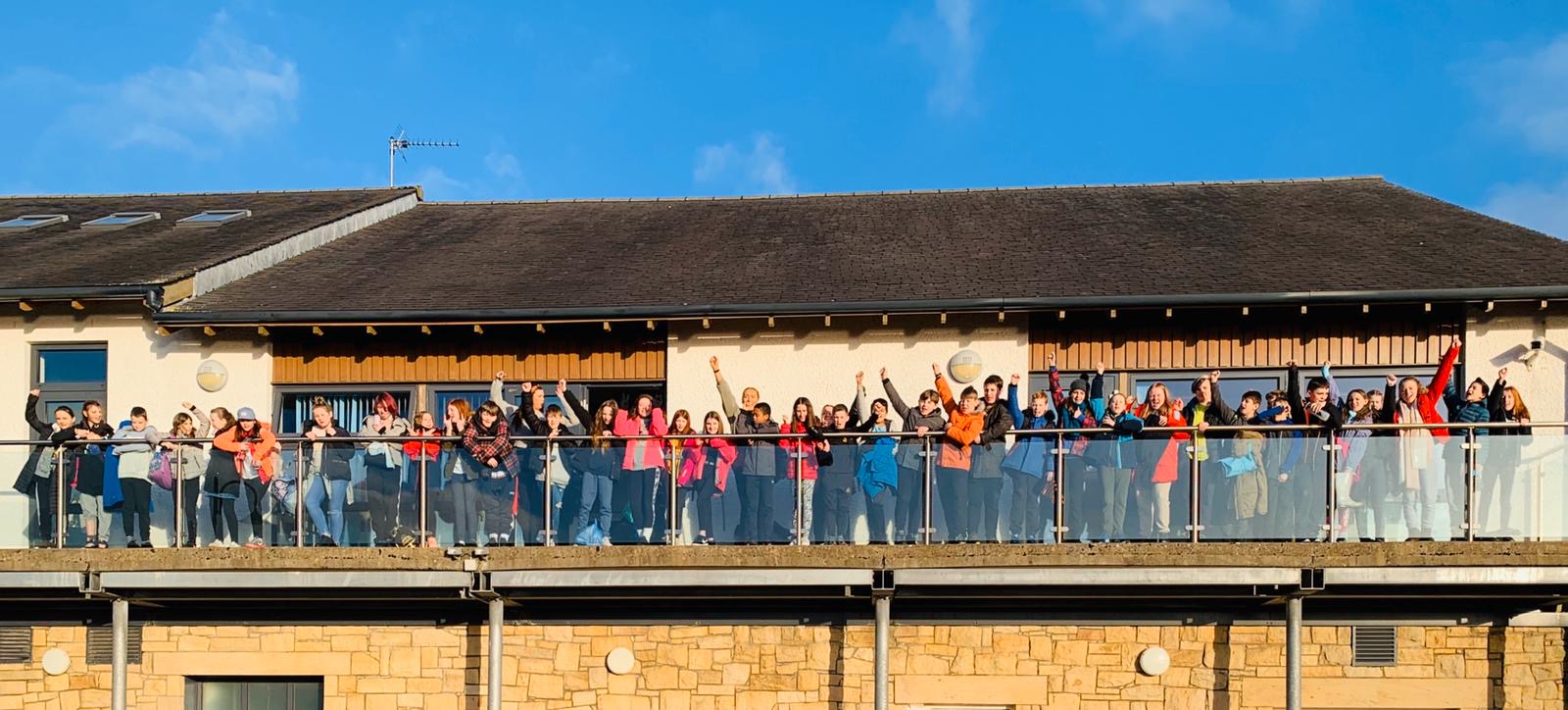 School group waving from a balcony.
