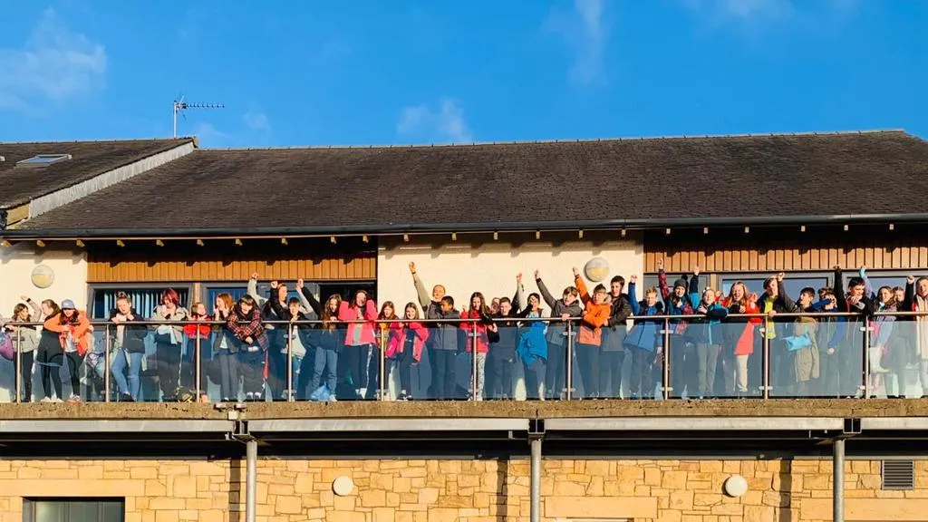 School group waving from a balcony.