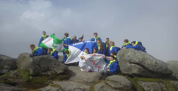 Young people display banners after climbing to the top of a summit