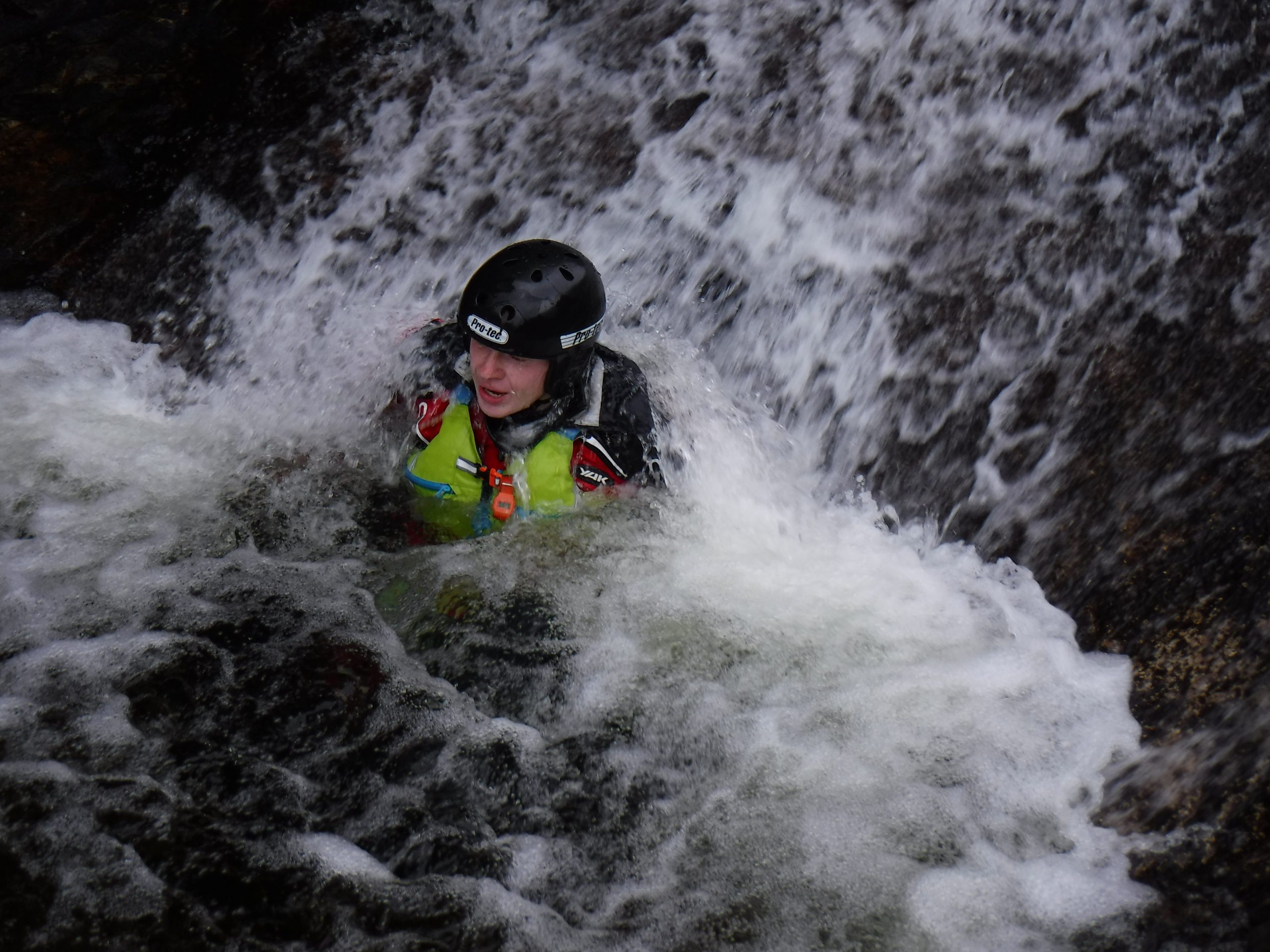 A child submerged in a waterfall during gorge walking activity
